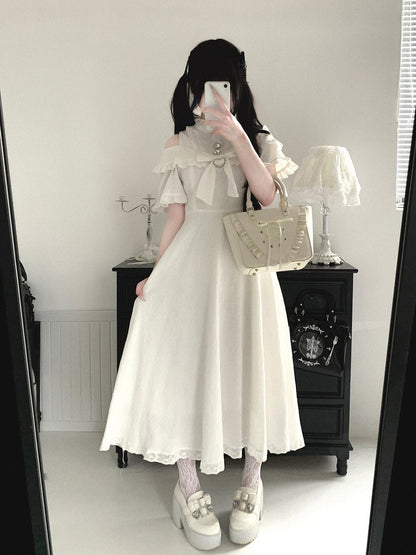 Person wearing a white dress with a lace top and skirt, holding a beige handbag in a room.