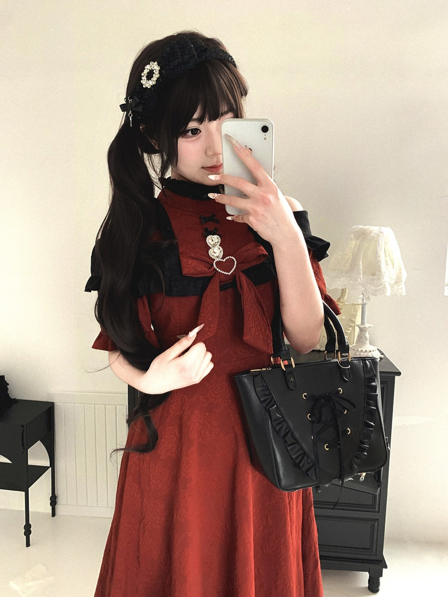 Woman in a red dress with black accents taking a selfie in a room.