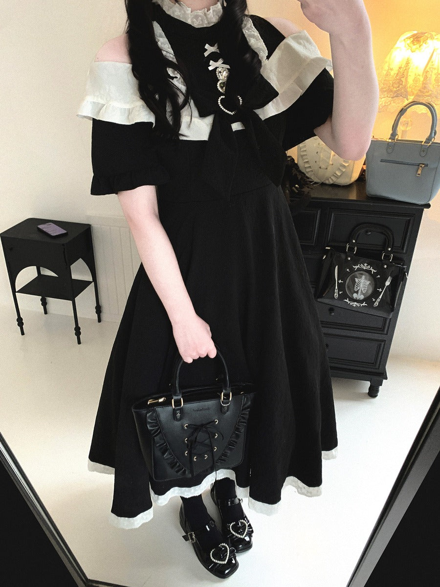 Person wearing a black and white outfit with a matching handbag in an indoor setting.