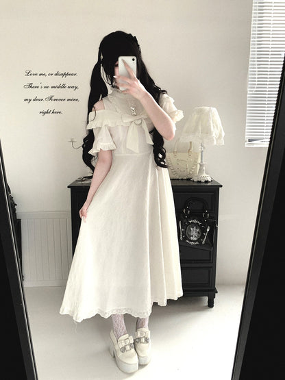 Person wearing a white dress with ruffled sleeves in a room.