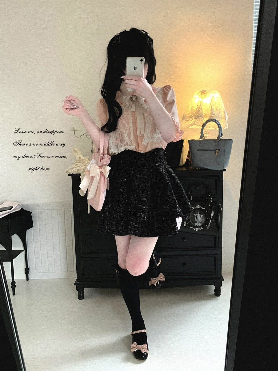 Person taking a mirror selfie wearing a lace top and black skirt in a room with a dresser and lamp.