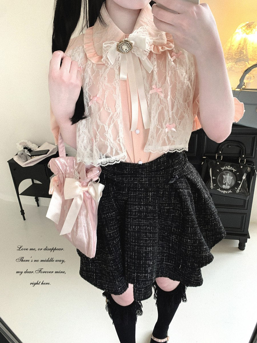 Person wearing a lace top and black skirt with a pink handbag indoors.