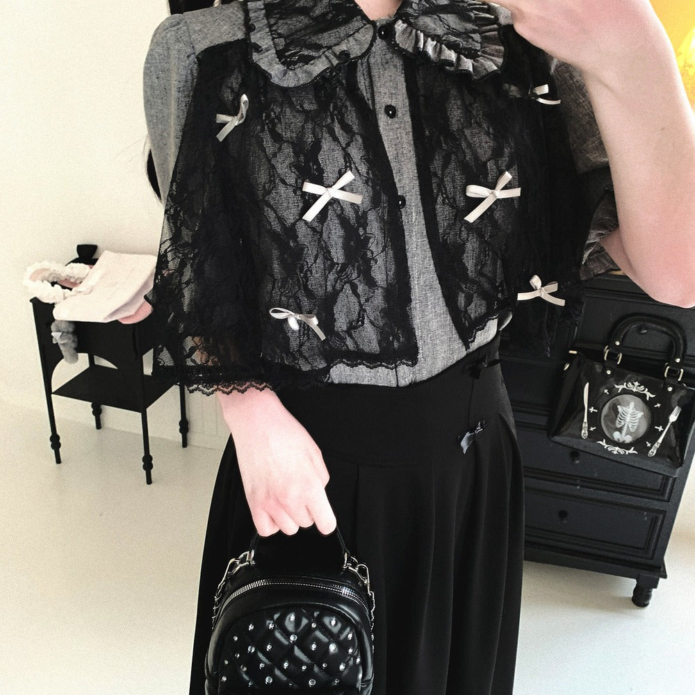 Person wearing a black lace top with white bows in a room with furniture.