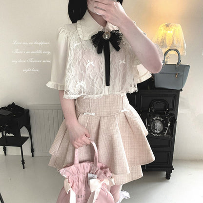Person wearing a white lace top and beige plaid skirt holding a pink bag in a room with a lamp and furniture.