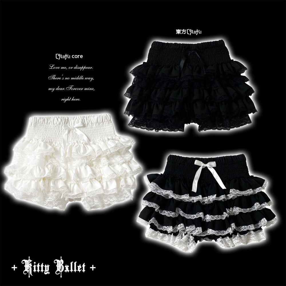 Three pairs of ruffled baby shorts displayed on a black background: one white pair, one black pair, and one black-and-white tiered pair with a white bow.