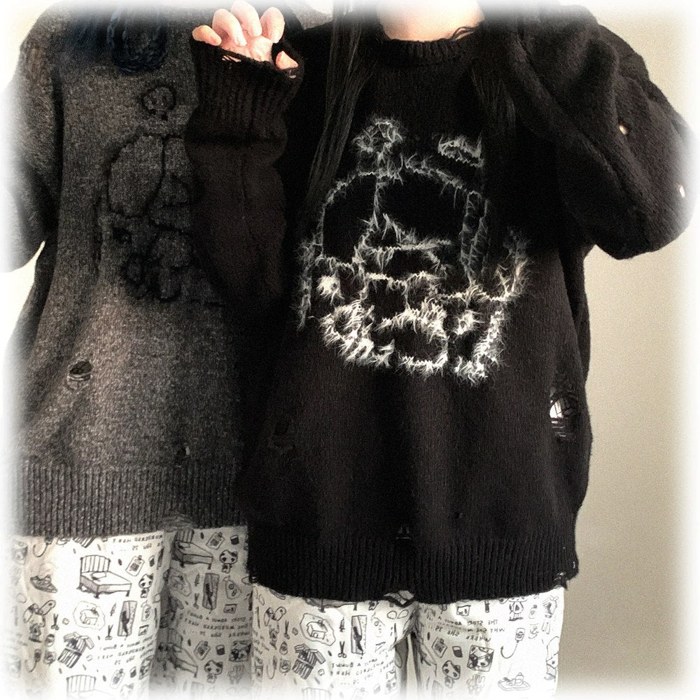 Two sweaters, one black with a skull design and the other gray, worn by a person.