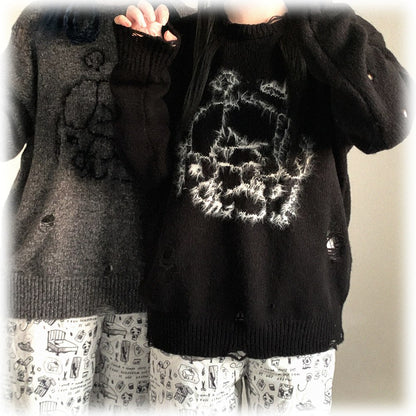 Two sweaters, one black with a skull design and the other gray, worn by a person.