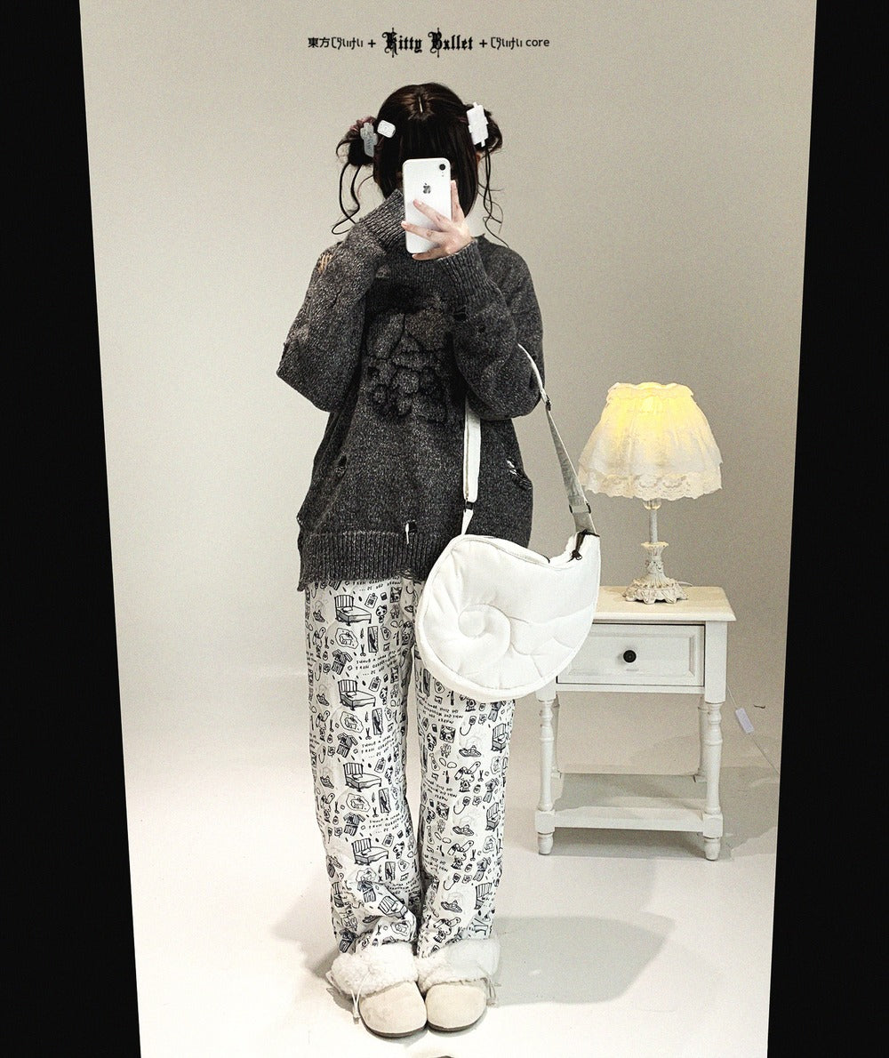 Person taking a mirror selfie wearing a dark sweater and patterned pants in a room with a lamp and small table.