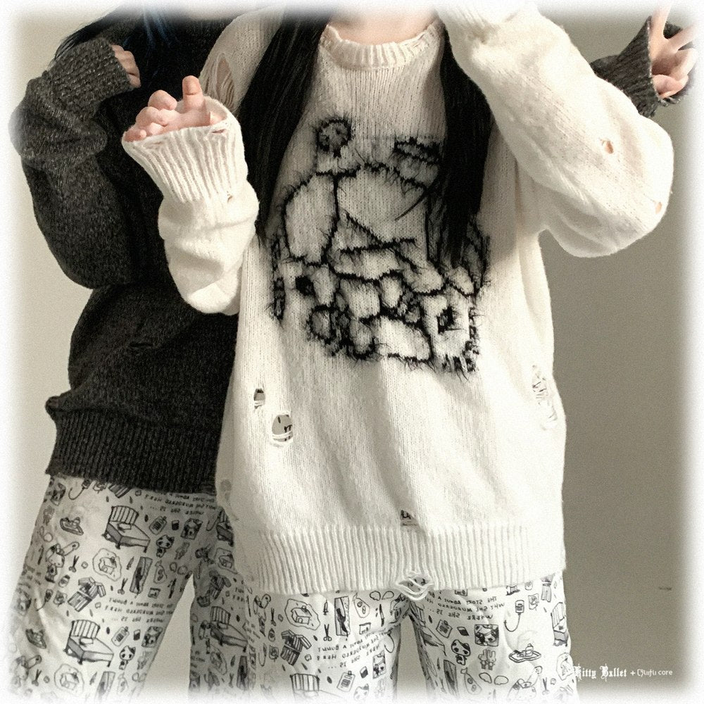 Person wearing a white cardigan with black design, black sweater, and patterned pants.