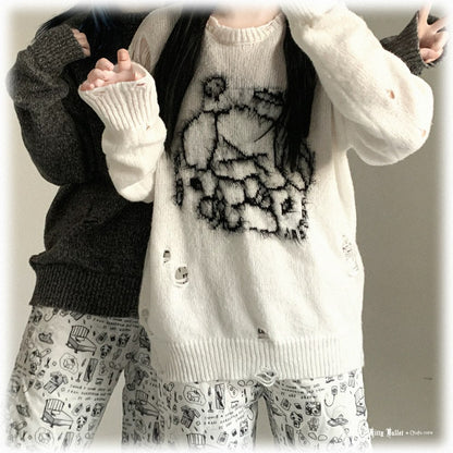 Person wearing a white cardigan with black design, black sweater, and patterned pants.