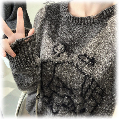 Close-up of a person wearing a gray sweater with a pattern.