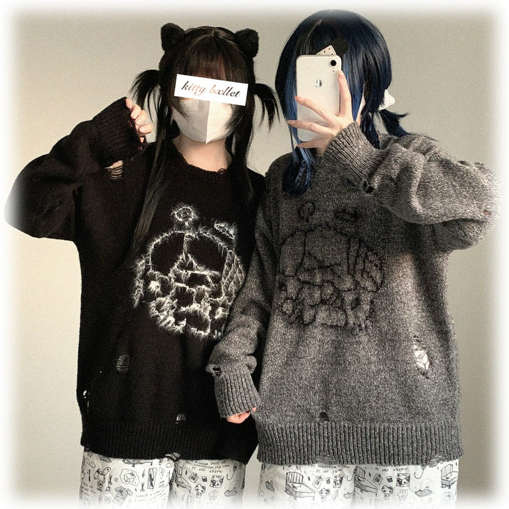Two people wearing matching black and gray sweaters with skull designs, standing against a plain background.