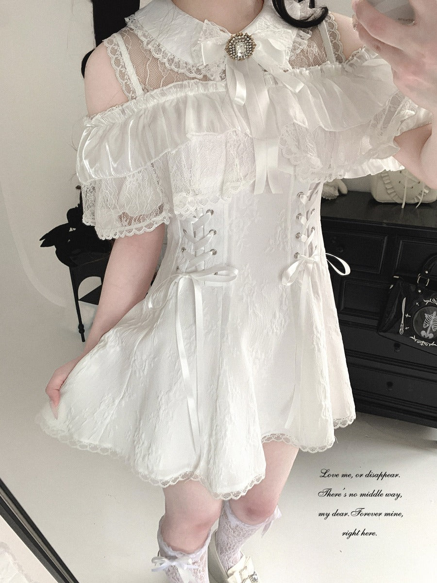 Person wearing a white lace dress with a decorative brooch in an indoor setting.