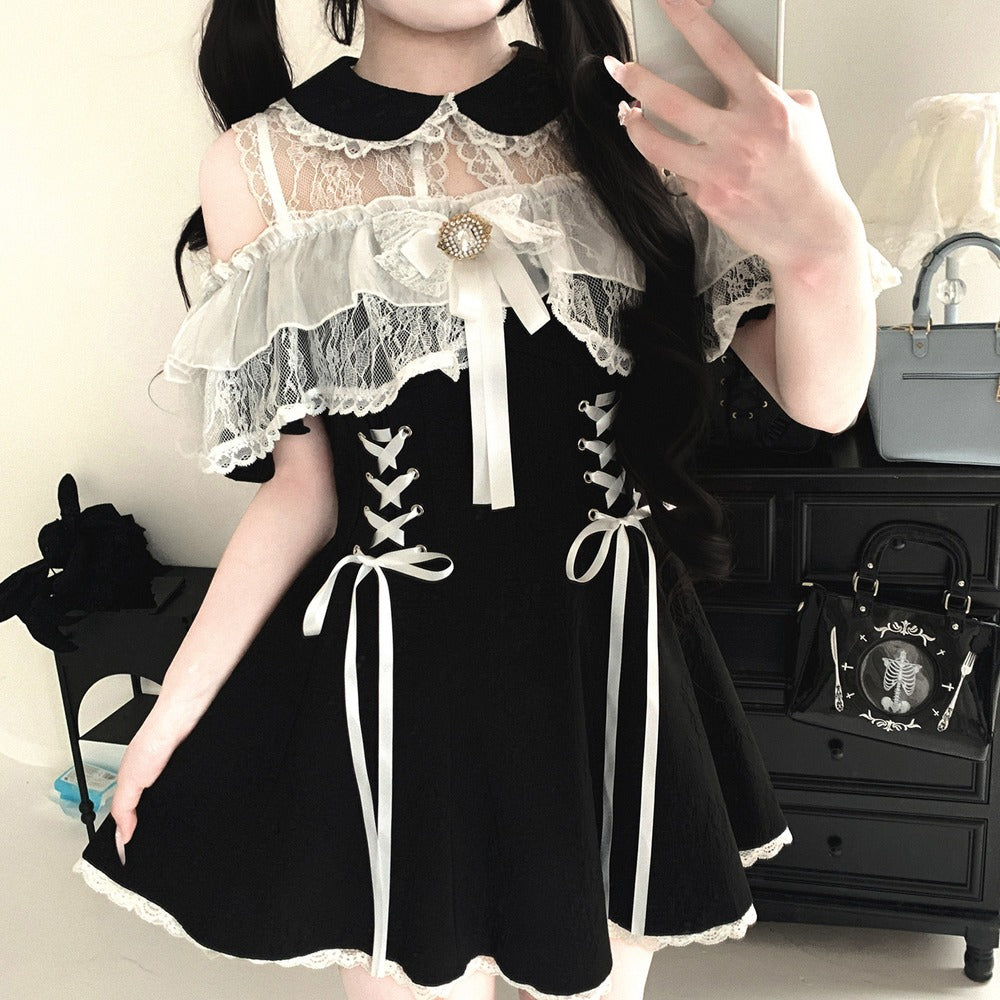 Person wearing a black and white dress with lace details, posing in a room.