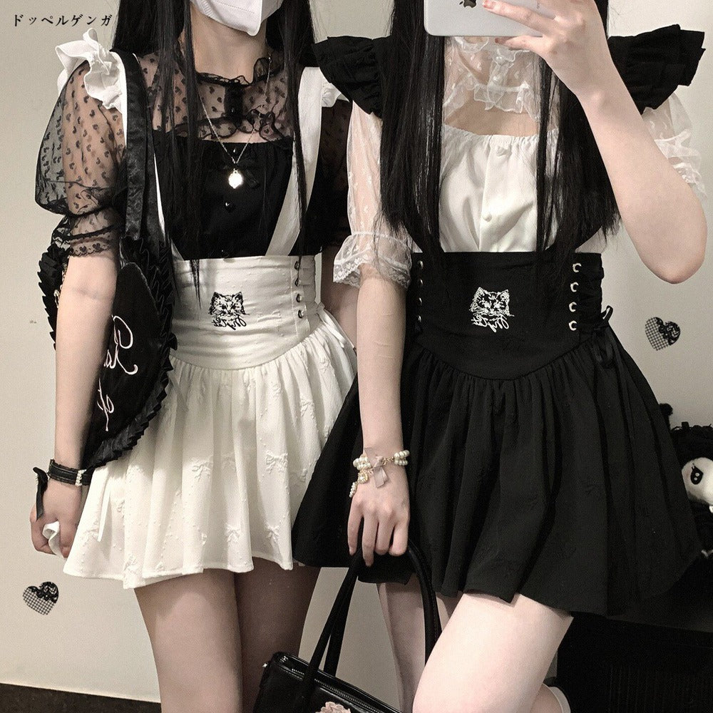 Two people wearing black and white outfits with cat designs, standing side by side.