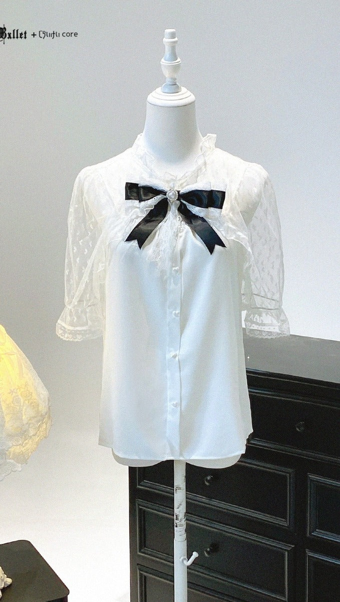 White lace blouse with a black bow on a mannequin against a gray background