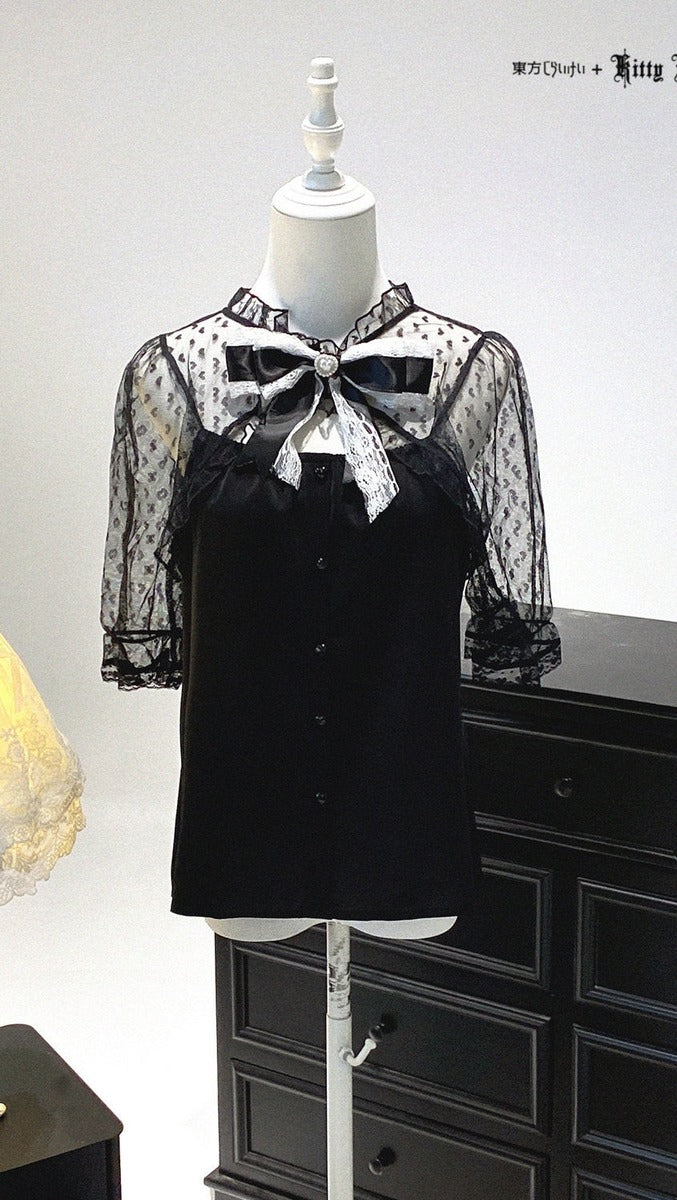 Black blouse with sheer sleeves and bow detail on a mannequin against a white background.
