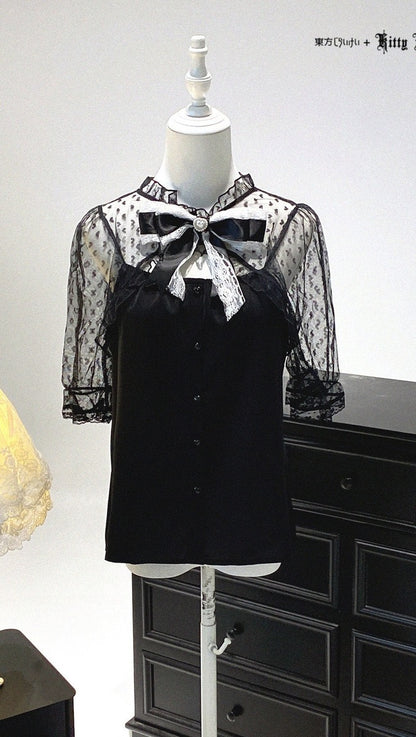 Black blouse with sheer sleeves and bow detail on a mannequin against a white background.