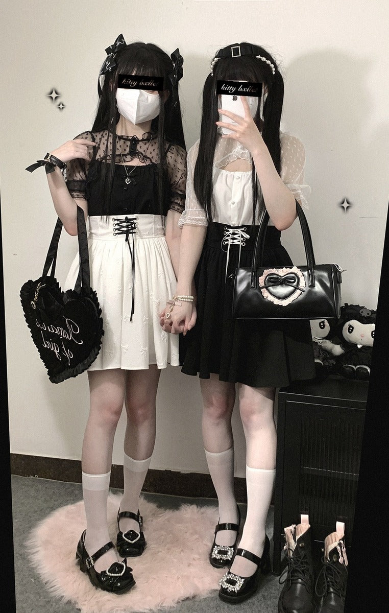 Two people in black and white outfits with handbags, standing in a room.