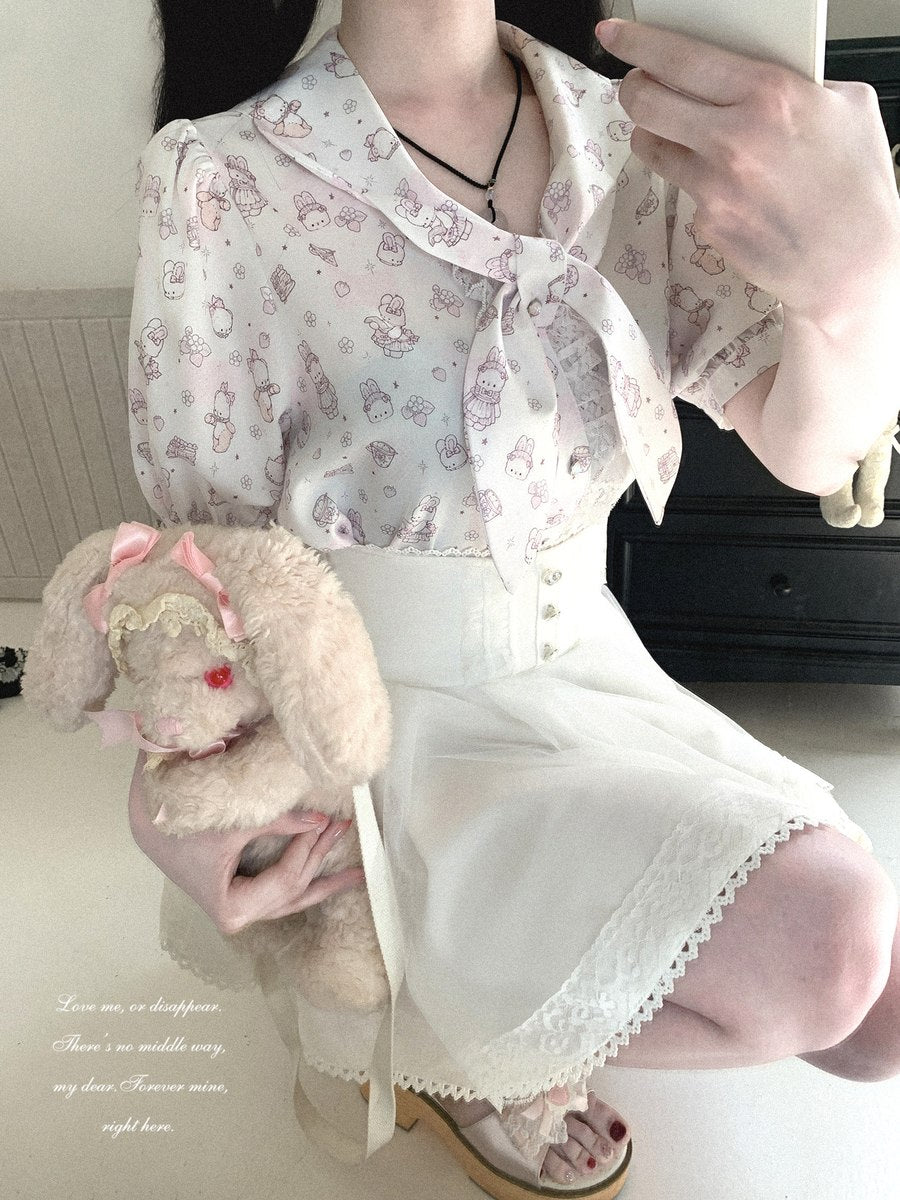 A person wearing a short-sleeve white blouse with a pink bunny print and a large bow collar, paired with a white skirt, holding a plush bunny toy in a mirror selfie.