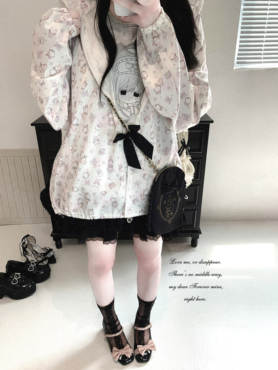 A person wearing a cream-colored Lolita-style jacket with a pink and white floral pattern, a black lace-trimmed mini skirt, black lace-up heels, and a black crossbody bag, standing in a room.