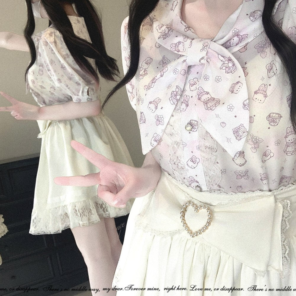 A close-up of a person wearing a pastel cream blouse with a large bow and a repeating Hello Kitty-style bunny print, paired with a cream skirt. A mirror in the background shows a full-length view of the outfit.
