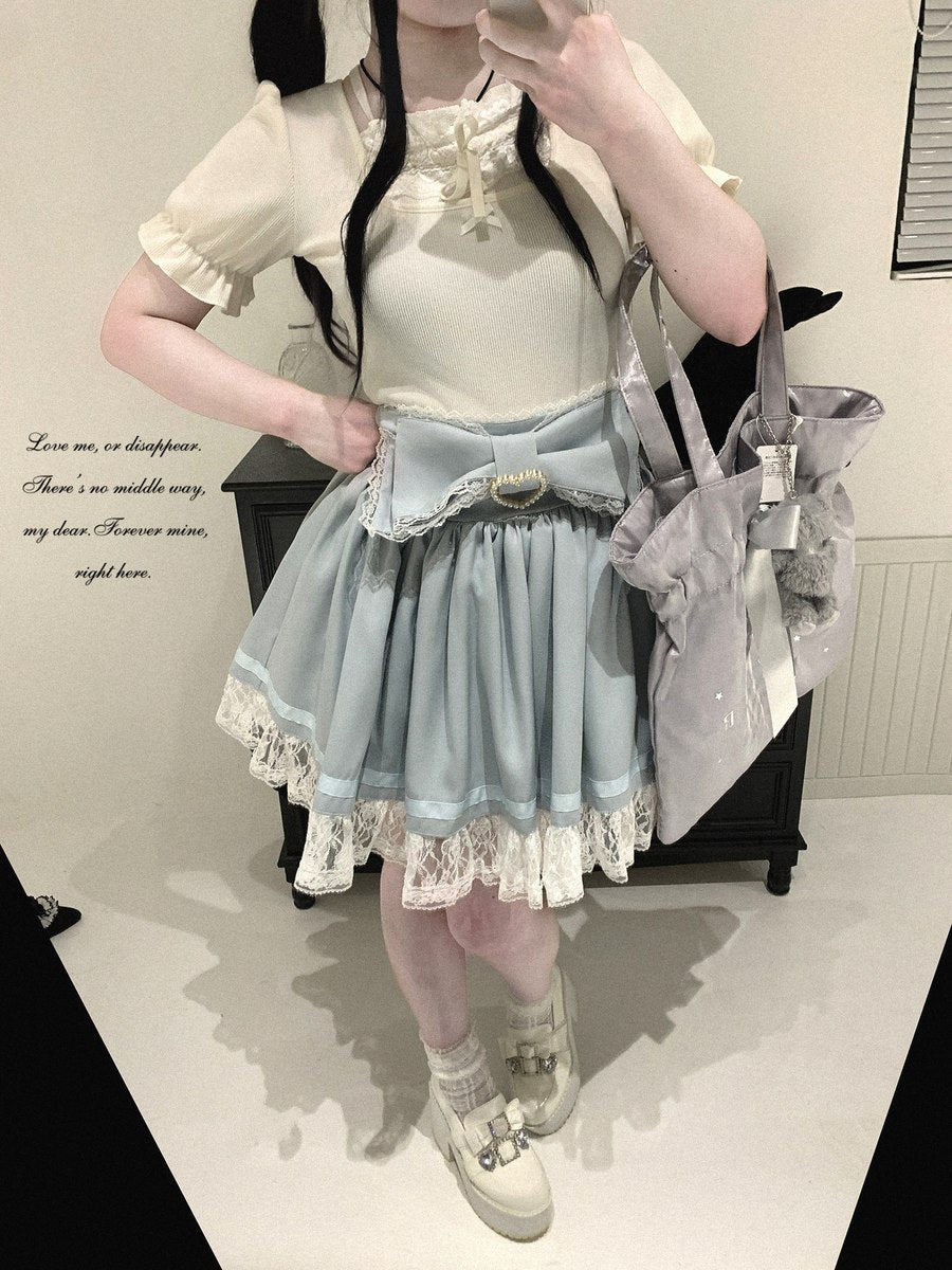 A person wearing a light blue and cream Lolita-style outfit with a pleated skirt, ruffled blouse, lace trim, and a large bow at the waist, holding a gray bag in a mirror selfie.