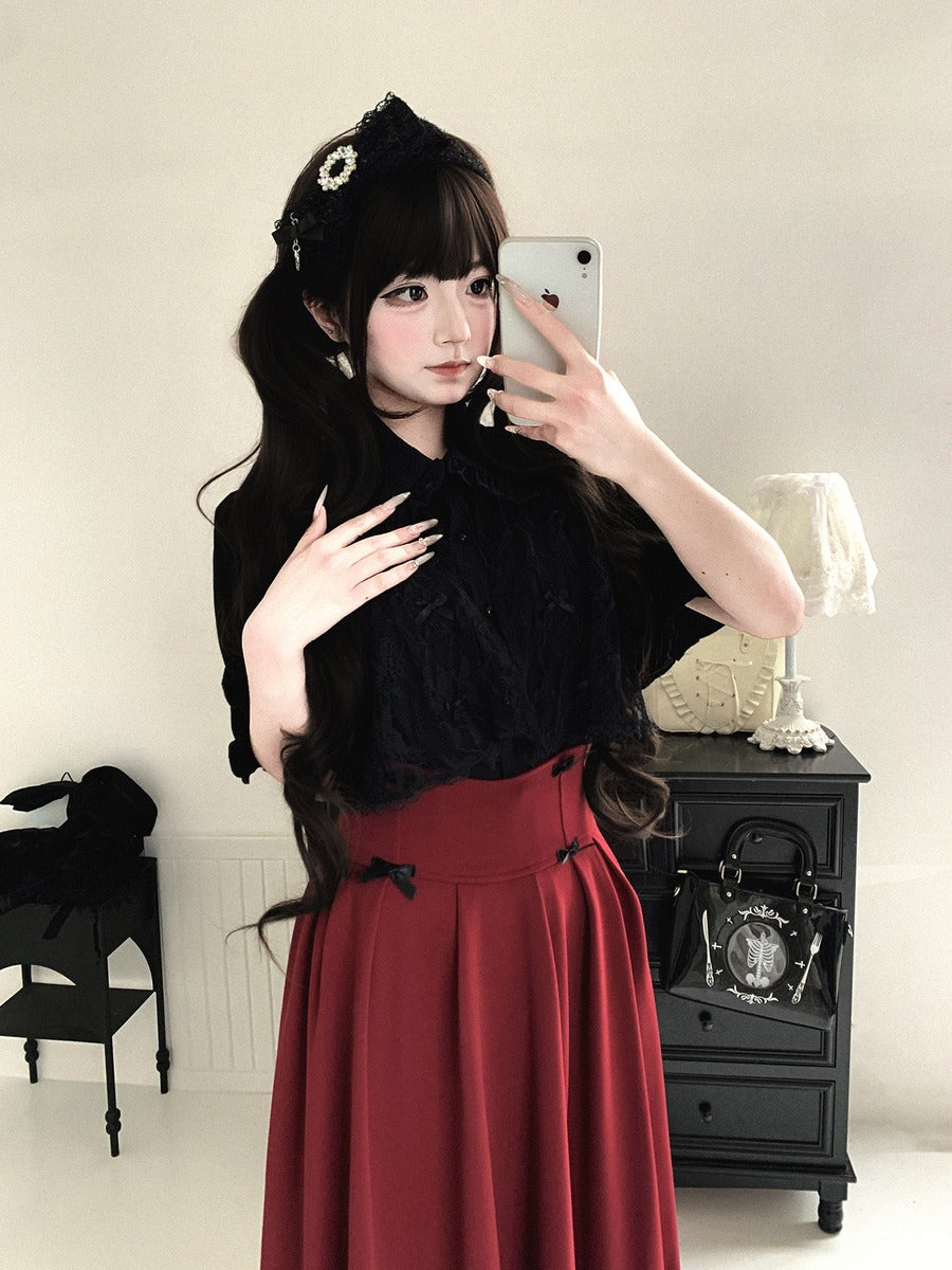 Woman taking a mirror selfie wearing a black top and red skirt in a room with a lamp and chair.