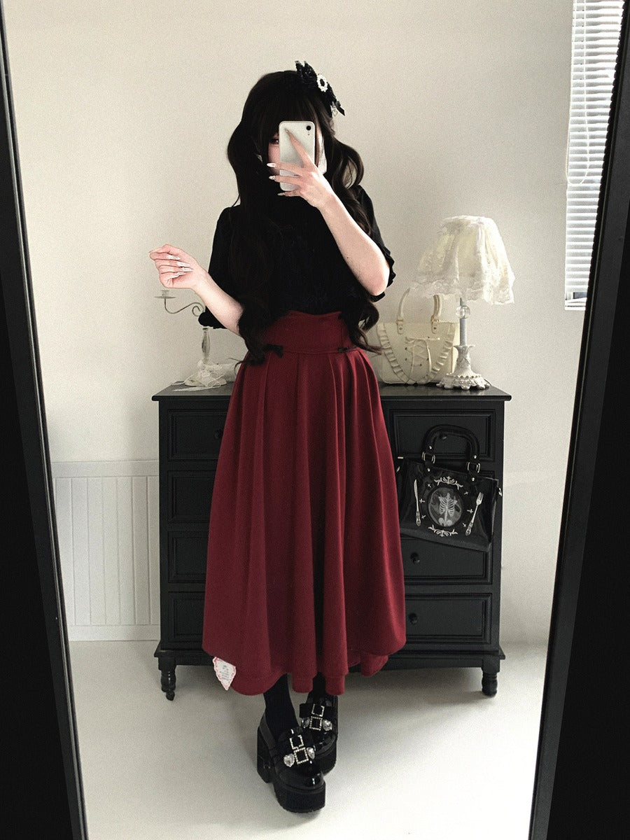 Person wearing a black top and red skirt standing in front of a mirror.