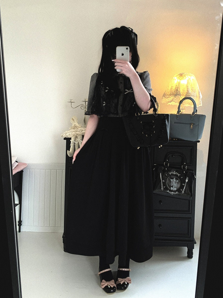 Person wearing a black outfit with a skirt, standing in front of a mirror.