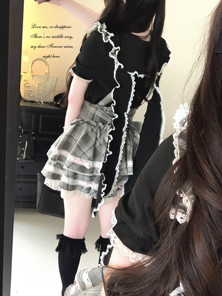 Person wearing a black top with lace trim and a plaid skirt in an indoor setting.