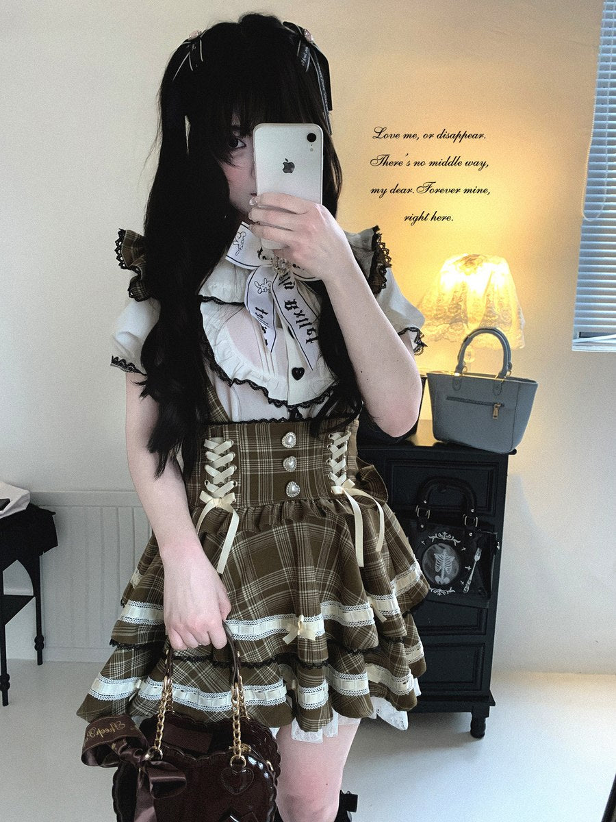 Person wearing a plaid dress with a white shirt, standing in a room with a lamp and window.