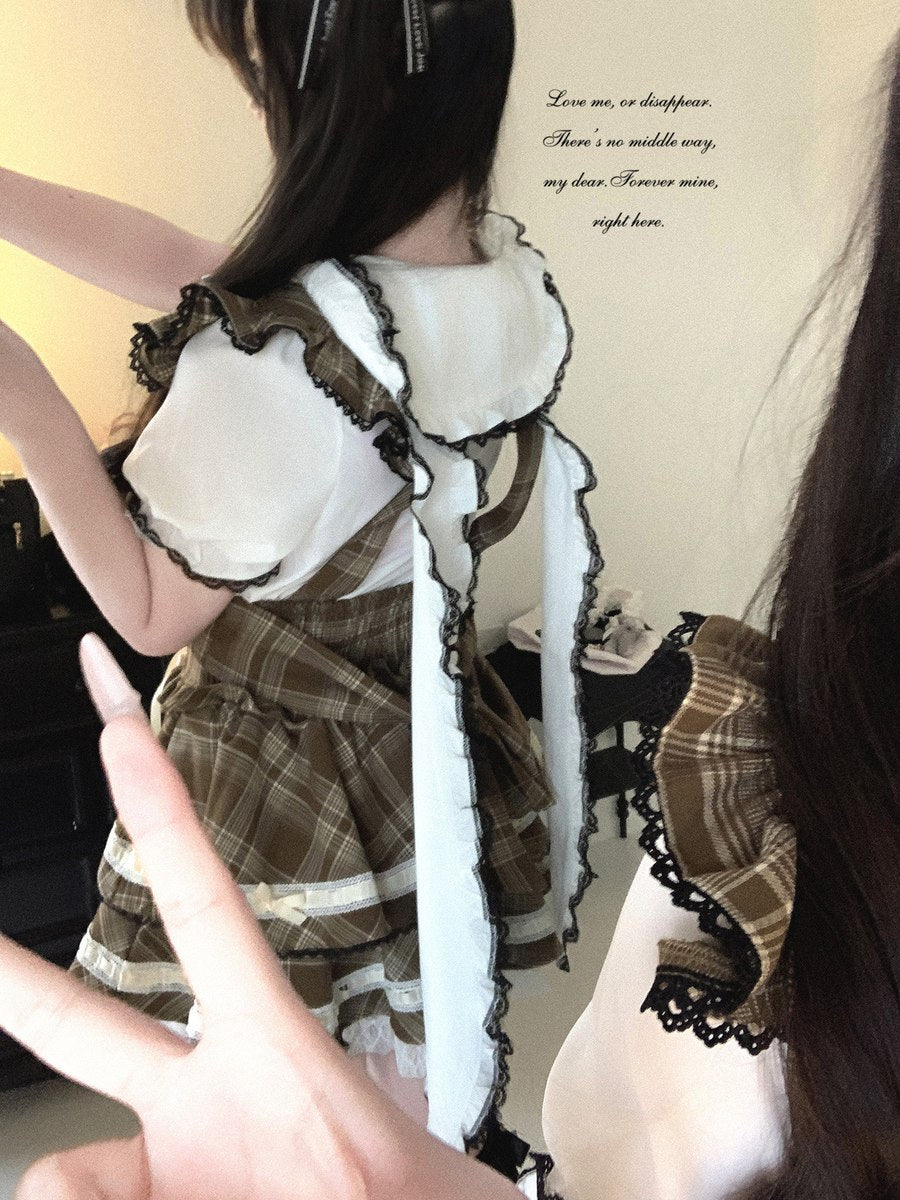 Person wearing a detailed outfit with lace and plaid patterns, pointing at themselves.