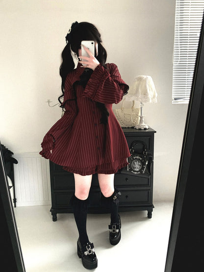 Person wearing a burgundy pleated dress with long sleeves in a room.