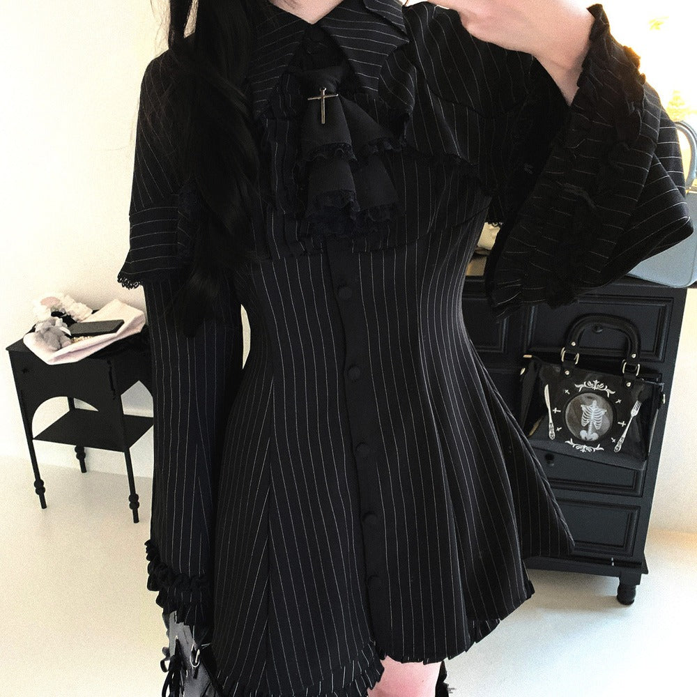 Person wearing a black pinstripe dress with ruffled details in an indoor setting.