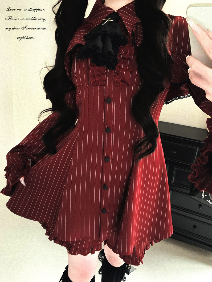 Person wearing a red and black striped dress with ruffled details, standing in front of a white wall.
