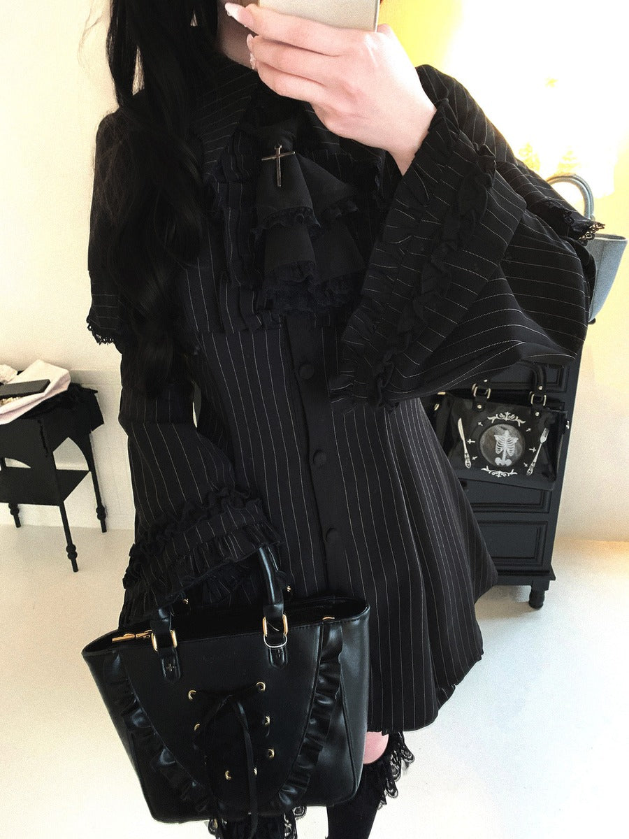 Person wearing a black outfit with ruffled details and holding a black handbag.
