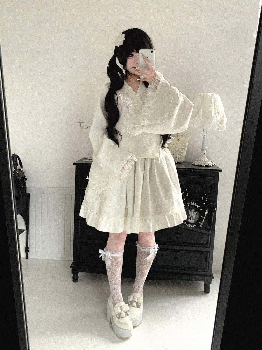 Person wearing a white kimono outfit with ruffles and lace, standing in front of a mirror.
