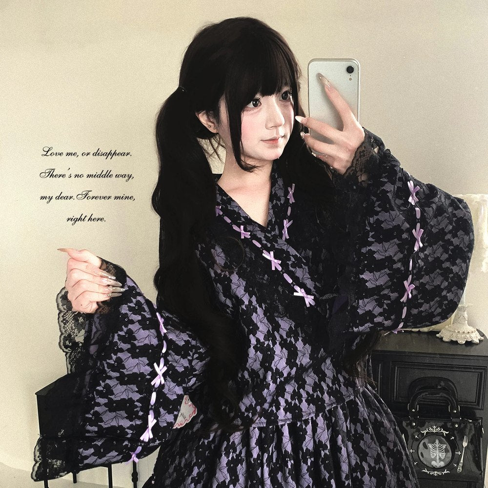 Person wearing a dark patterned kimono dress with sheer sleeves, taking a selfie.