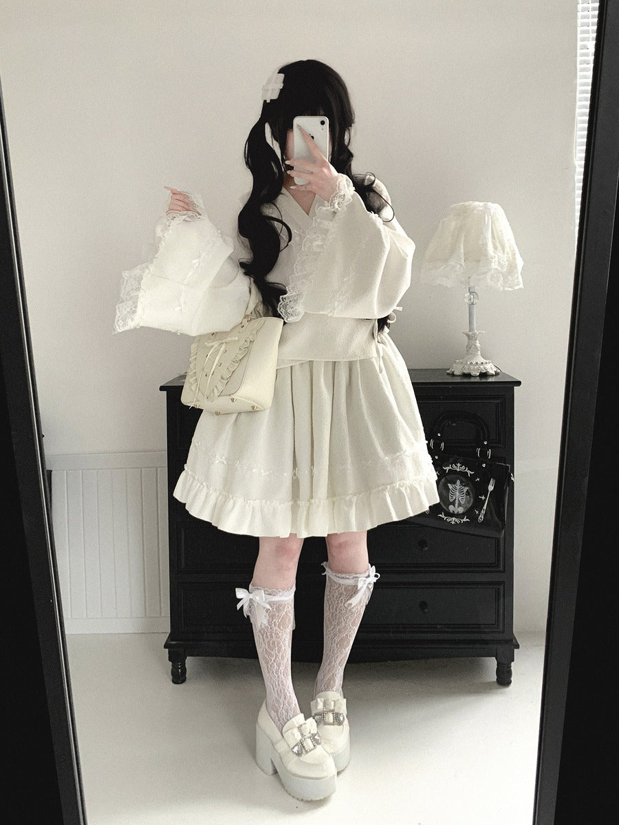 Person wearing a white kimono outfit with ruffled sleeves and a skirt, standing in front of a mirror.