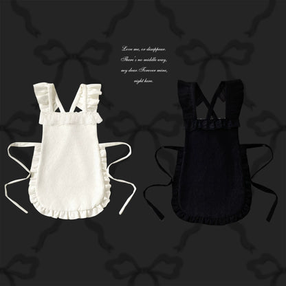 White and black apron on a dark background with decorative bows.