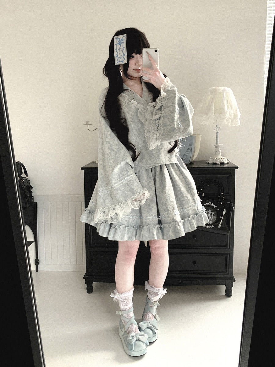 Person wearing a light gray lace kimono dress in a room with a mirror.