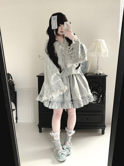 Person wearing a light gray lace kimono dress in a room with a mirror.
