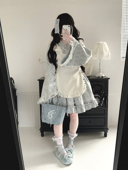 Person wearing a detailed kimono outfit with a white shirt, gray skirt, and light blue shoes in a room.