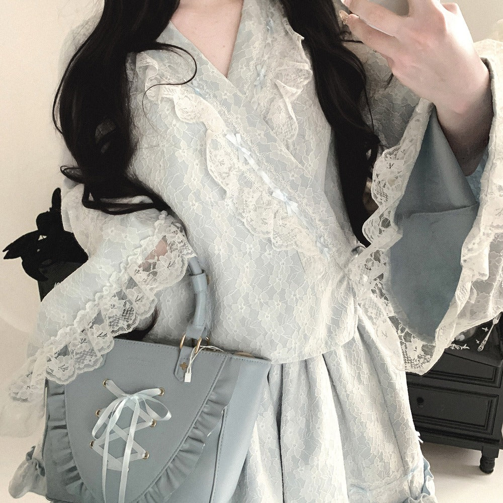 Person wearing a light blue kimono dress with lace details, holding a matching bag.