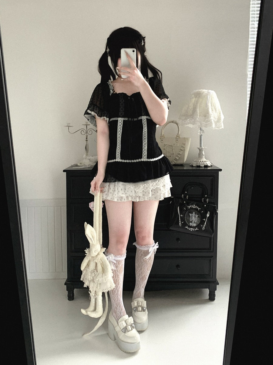 Person wearing a black and white outfit with lace details, standing in front of a mirror.