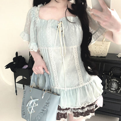 Person wearing a light blue dress with lace details in an indoor setting.