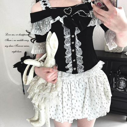 Person wearing a black and white outfit with lace details, holding a white rabbit plush toy.