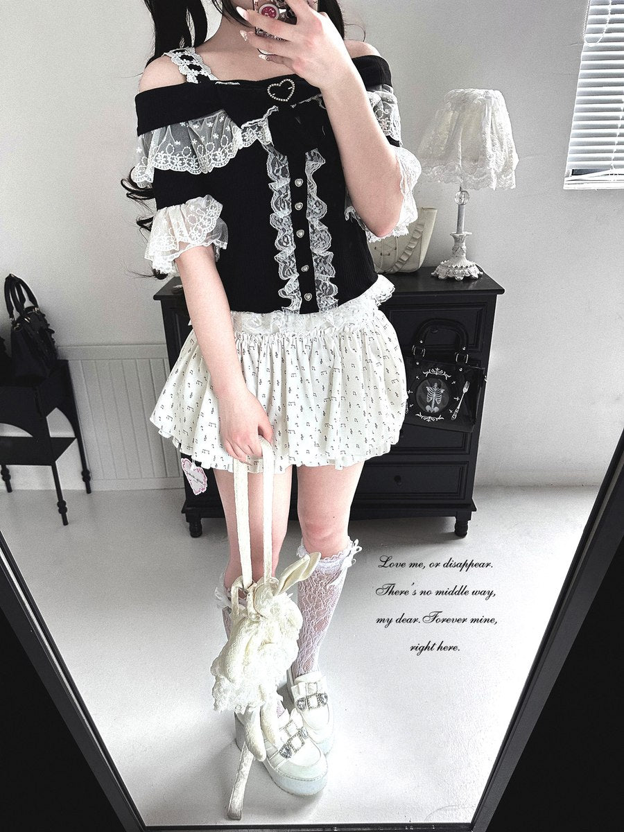 Person wearing a black and white outfit with lace details in a room.