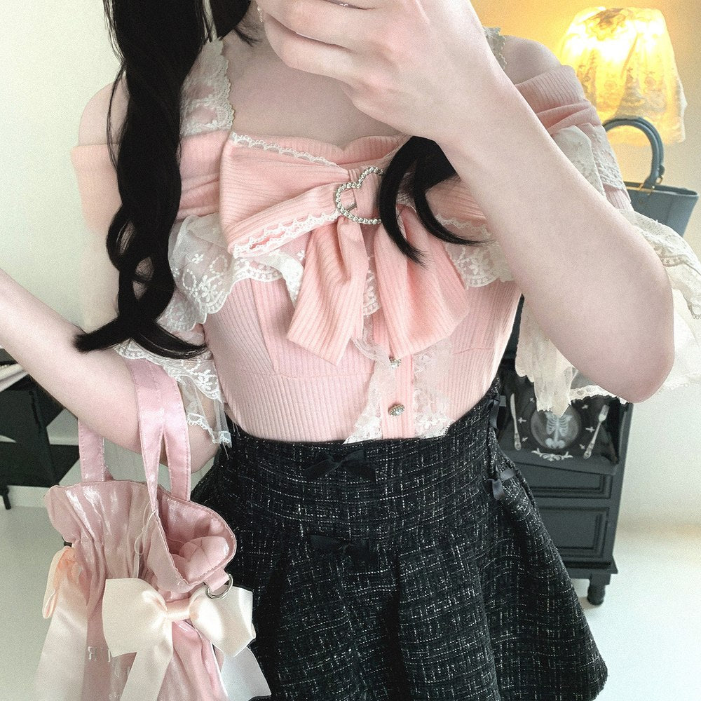 Person wearing a pink top with lace details and a black skirt indoors.